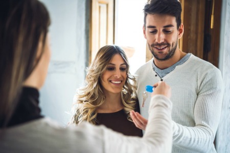 Smiling man and woman accepting keys after buying a house