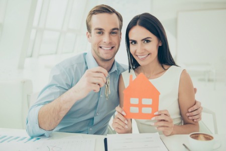man holding keys and woman holding house cut out