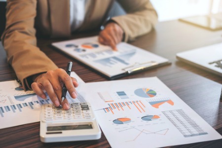 real estate market concept woman using calculator that is sitting on graphs